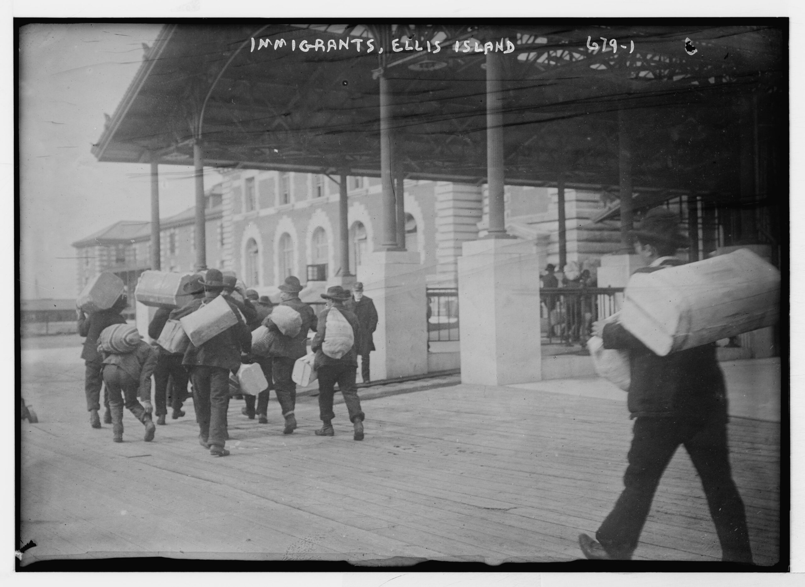 Immigrants_carrying_luggage,_Ellis_Island,_New_York_LCCN2014683247(1)